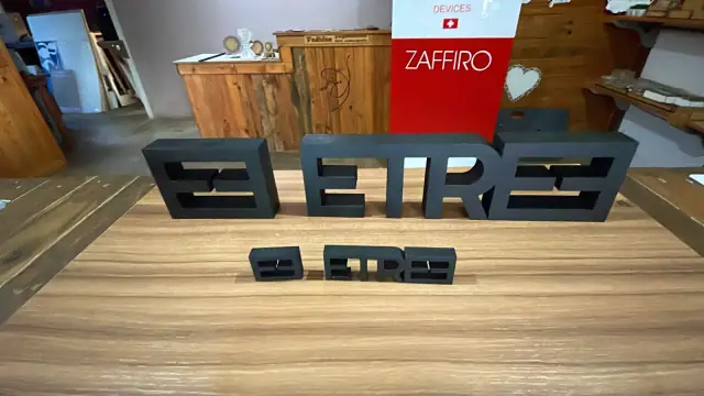 Letras tridimensionais pretas em diferentes tamanhos sobre uma mesa