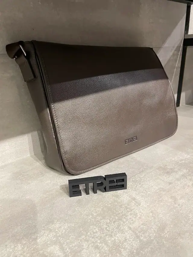 Logo preto em relevo exposto ao lado de uma bolsa
