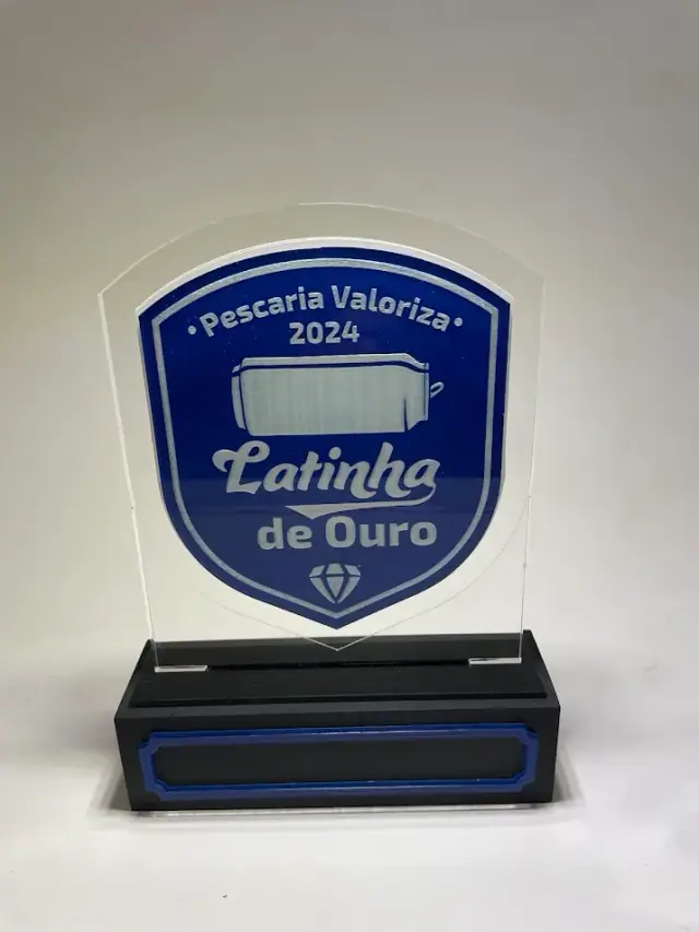 Troféu azul com inscrição Latinha de Ouro sobre base preta com detalhes azuis