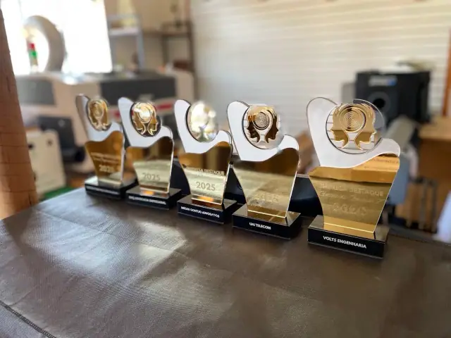 Troféus brancos e dourados com medalhões de perfil humano e bases pretas