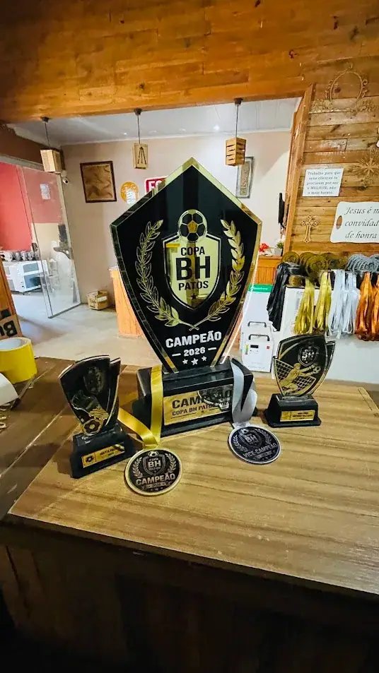 Troféu grande preto e dourado com bola de futebol, troféus menores e medalhas