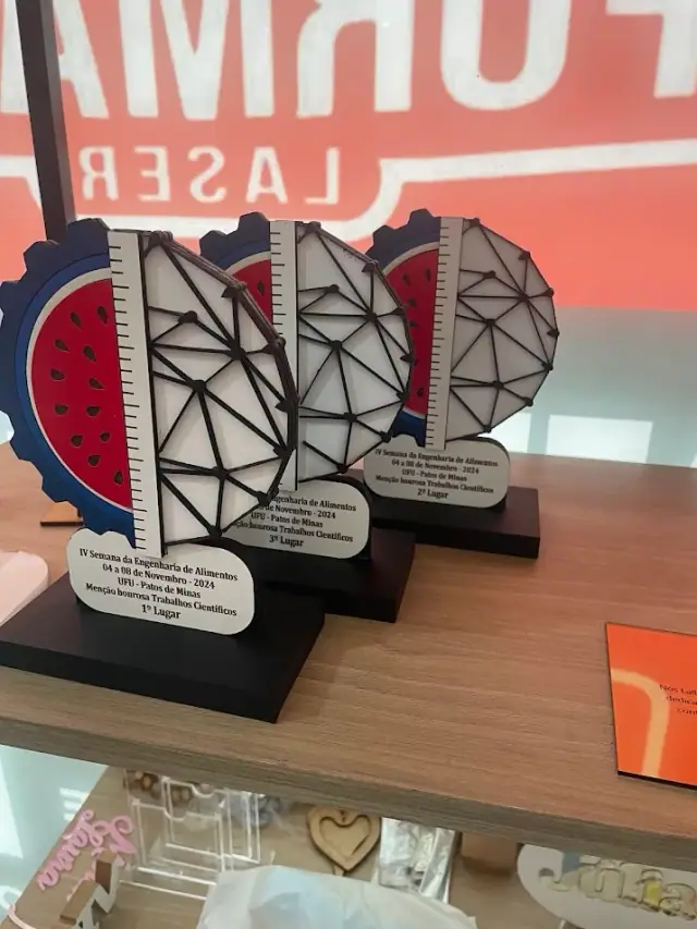 Troféus com formas geométricas recortadas e placas claras sobre bases pretas