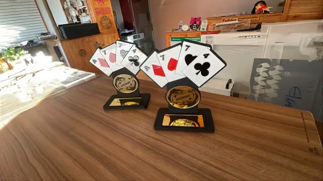 Troféus com cartas de baralho, medalhão circular e base preta