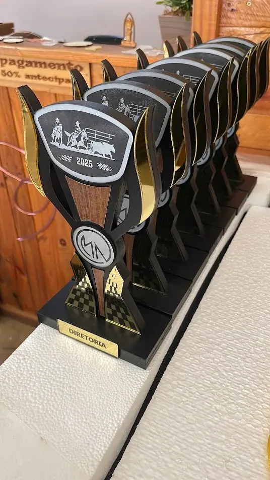 Fileira de troféus pretos e dourados com silhuetas de cavalos e cavaleiros